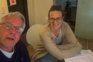 Jürgen Wolf und Klara sitzen zusammen an einem Tisch mit Unterlagen und führen ihr Interview-Gespräch – Jürgen Wolf Kommunikation
